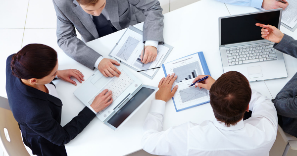 Business professionals collaborating at a conference table, reviewing charts and documents related to energy efficiency and electrical systems.