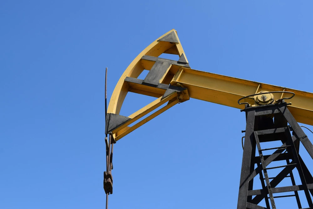 Oil pump jack against a clear blue sky, representing non-renewable energy sources and their environmental impact.